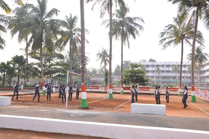 Volleyball court among palm trees with the hostel block behind